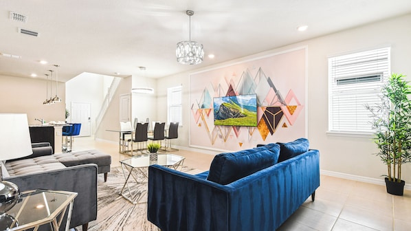 Movie nights made easy! This living room features a large flat screen TV mounted on the wall, comfy couches, and colorful chairs for movie marathons!