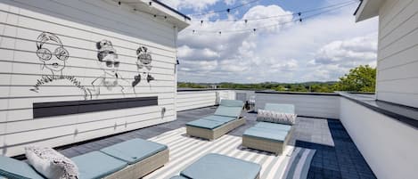 4th Floor: Private rooftop deck featuring a personalized mural, lounge chairs, bistro lighting, and an additional dining area overlooking a beautiful Nashville skyline view.