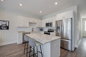 2nd Floor: Fully equipped modern kitchen stocked with all culinary essentials boasting stainless-steel appliances and a kitchen island offering bar seating.