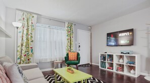 Living room with smart tv, bright colors, games, and books