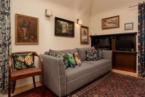 A cozy living room with a vintage sofa, decorative artwork, and warm lighting.

