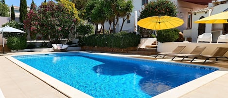 Piscina com espreguiçadeiras e guarda-sóis no terraço