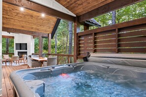 A private hot tub deck equipped with a spacious tub and a view of the surrounding woods