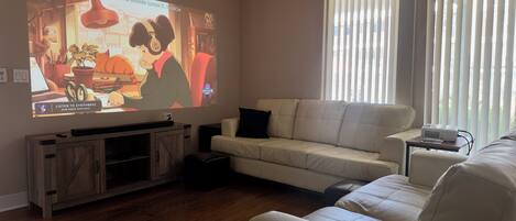 Living room with projector, Apple TV 4k, speaker + sub, and pullout couch