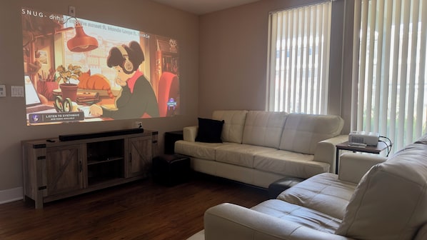Living room with projector, Apple TV 4k, speaker + sub, and pullout couch
