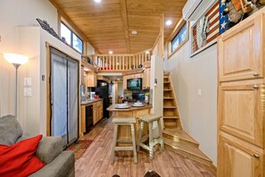 View of the tiny cabin's kitchen, bar seating and stairs to the upstairs sleeping loft