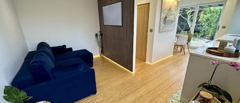 Living room with double sofa bed, 50" Samsung Smart TV, and LED accent lighting.