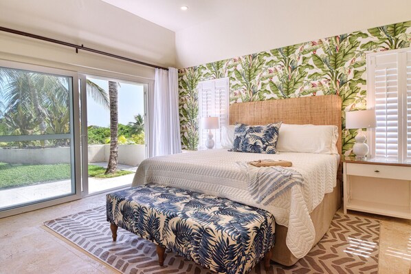 Airy main bedroom with king bed opening onto a serene patio and tropical garden.