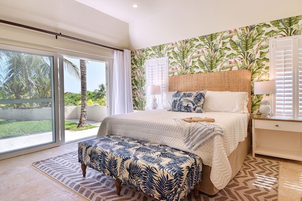Airy main bedroom with king bed opening onto a serene patio and tropical garden.