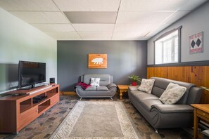 Family room featuring a TV, cozy grey sofa, and stylish grey accent wall—perfect for comfortable entertainment and relaxation.