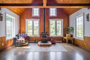 Spacious living room with high ceilings, wood-themed decor, and a cozy fireplace—perfect for relaxing in style and warmth.