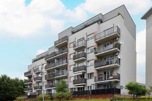 An exterior view of a contemporary apartment building, surrounded by greenery.


