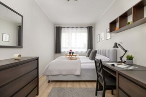 A stylish bedroom featuring a double bed, built-in storage, and a workspace by the window.

