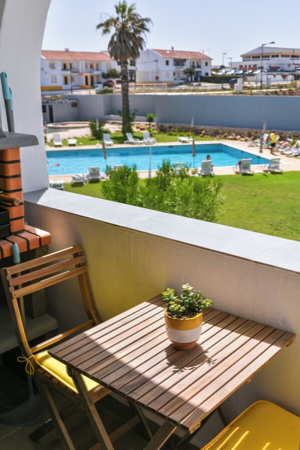 Balcony with BBQ grill and pool view.