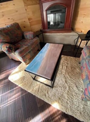 Living room c/w electric fireplace, large chairs and crashing waves coffee table