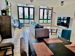 Part of dining room with the living room and 2-story high windows in background.