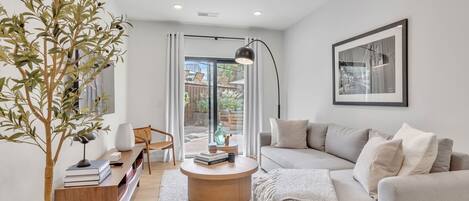 Modern living room offering an inviting and cozy space to relax and unwind featuring a Smart TV for entertainment and a sliding glass door to the shared communal areas including a sparkling blue pool.