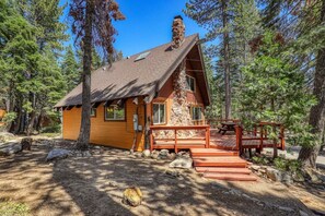 The view of the front of the home where you will be greeted by a spacious front deck that includes a wooden picnic table.