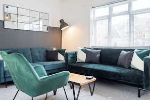 Vibrant living room featuring luxurious cottony green sofas and a matching chair. The lush green hues add a touch of elegance and freshness to the space.