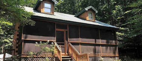 TokaTime log cabin has a long screen-in porch and a woodsy view.