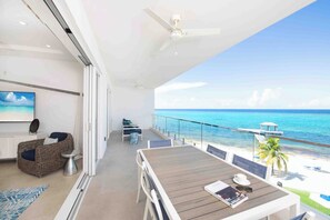 Private oceanfront balcony furnished with an al fresco dining table and sofa seating. 