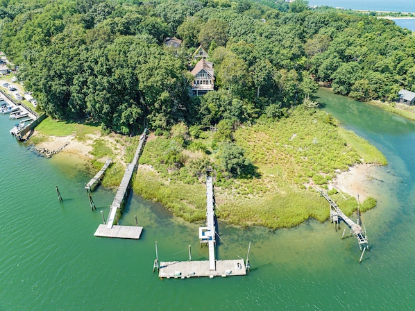 A breathtaking bird's-eye view capturing the expansive property, complete with a stretching private dock reaching out into the serene waters.