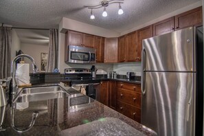 Fully stocked kitchen with spices, cookware and coffee pods.