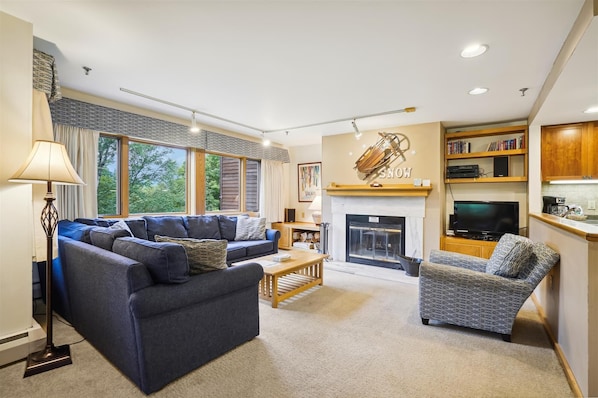 Spacious living room with soothing bright colors. Natural light from the large windows which offer a serene views of the surrounding landscaping of Highridge
