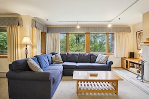 Spacious living room with soothing bright colors.  Natural light from the large windows which offer a serene views of the surrounding landscaping of Highridge