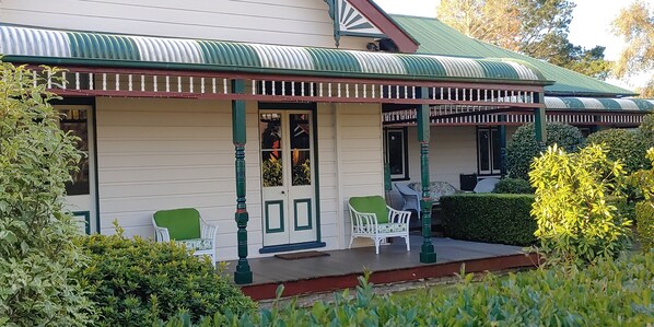 Relax in a chair on the front verandah overlooking the mature garden