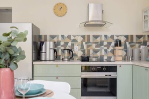 A modern kitchen with pastel green cabinets, patterned backsplash, and sleek appliances.


