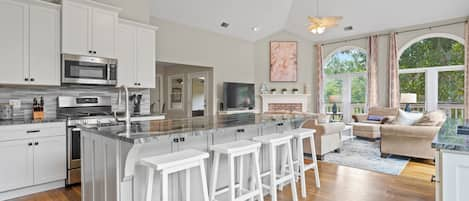 Open concept kitchen with beautiful countertops, gas stove, and island with seating for 5. Sliding door leading to deck.