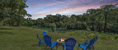 Seating around a firepit overlooking the river at the back of the property