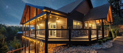 A cozy cabin glows under a starry night sky, perfect for a peaceful evening escape.