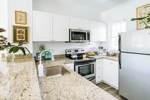 Uncluttered kitchen features granite countertops & stainless-steel appliances.