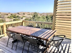 8-top dining table with glimpses of the Atlantic Ocean between the dunes.