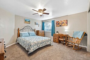 Large carpeted bedroom with Queen size bed and private desk.