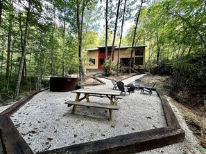 Down below the cabin is the fire pit, hot tub, and table. 