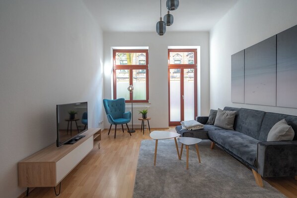 Gemütliches Wohnzimmer mit Netflix-TV, Lesesessel und Schreibtisch