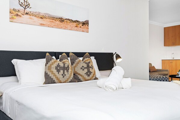 A stylish and comfortable bed. The crisp white bedding, fluffy towels, and statement cushions create a haven of tranquility.  Perfect for a peaceful night's sleep after a long day exploring.
