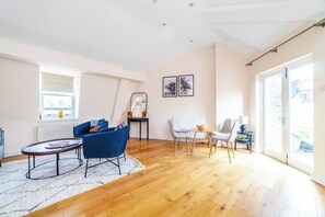 Large open plan sitting room and dining area with balcony overlooking London skyline