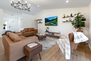 Bright & airy mid-century modern living room, real-leather sofas, fine art.