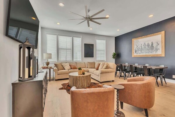 Inviting living area with a huge smart tv, custom design touches, and plenty of seating to gather and dine with your group.