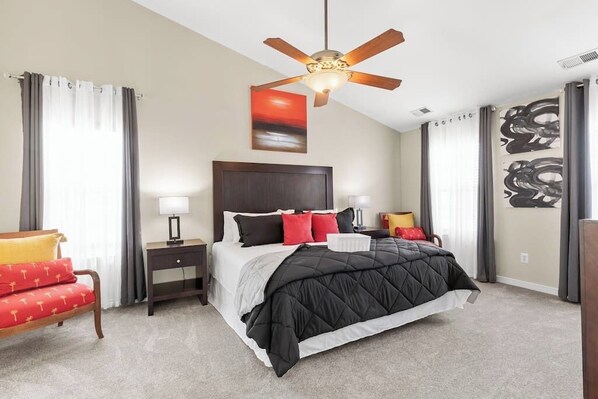 King-size comfort with a flat-screen TV, dresser storage, additional seating, ceiling fan, and a spa-like ensuite master bathroom.