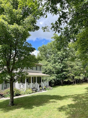 Charming countryside retreat! Relax on the wraparound porch or enjoy the spacious green yard under the serene shade of mature trees