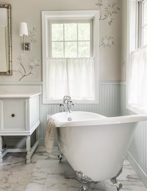 Relax in a spa-like bath with a clawfoot tub and elegant, serene decor.