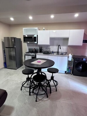 View of the fully functional kitchen and washer/dryer combination machine.