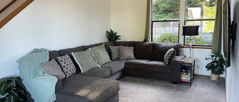 Living room #1 with an over sized sectional couch and a smart tv.