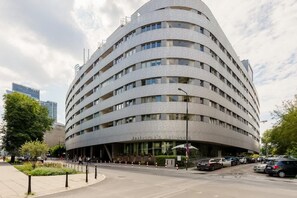An exterior view of the modern apartment building, showcasing its unique, curved architecture and surrounding greenery.

