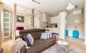 A spacious living room featuring a comfortable gray sofa, decorative cushions, and large windows bringing in natural light.